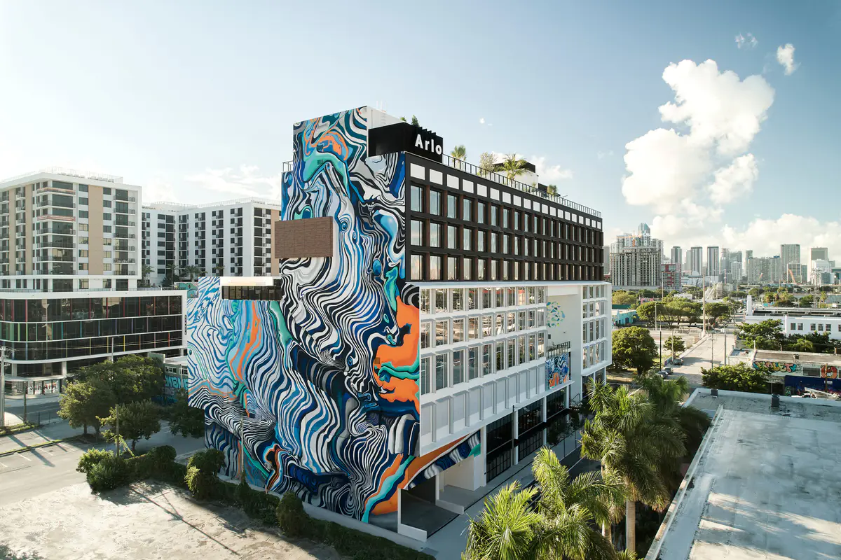 Arlo Wynwood hotel exterior with its rooftop sign and mural-covered facade